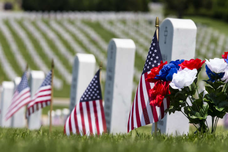 Flowers and Flags among cemetery grave sites.